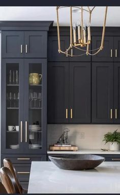 a modern kitchen with black cabinets and white counter tops, gold chandelier hanging from the ceiling