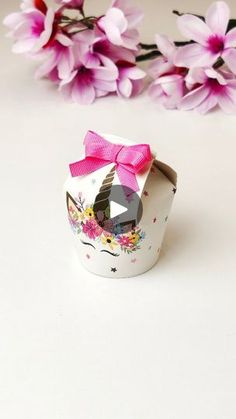 a small cupcake box with a pink bow on it and flowers in the background