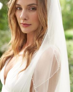 a woman wearing a white veil with pearls on it