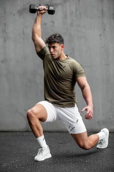 a man is squatting while holding two dumbbells in one hand and lifting the other