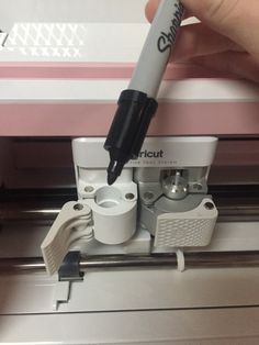 a person is using a machine to cut paper with a pen on top of it