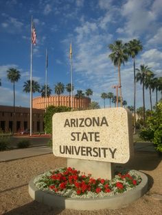 the arizona state university sign is in front of some palm trees and red flowered plants