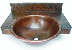 a copper colored bowl sink sitting on top of a wooden stand with a white background