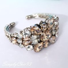 This listing is for the bracelet only Beautiful Bridal Bracelet Art Deco style . Made with clear crystals , white opal, and gold shadow stones set in rhodium plated metal. This bracelet is about 1 1/4 inches wide This is an open bangle so it will fit any wrist size. Matching hair comb at this link: https://www.etsy.com/listing/708567420/gold-shadow-crystal-hair-combwhite-opal?ref=shop_home_active_1 Please contact me if you have any questions. Hand crafted with Love. Handmade Cuff Bracelets For Weddings, Elegant Handmade Wedding Bangle, Elegant Cuff Wedding Jewelry, Elegant Cuff Jewelry For Weddings, Elegant Handmade Wedding Cuff Bracelet, Elegant Handmade Cuff Bracelet For Wedding, Handmade Wedding Cuff Bracelet, Handmade Cuff Bracelet For Wedding, Elegant Handmade Crystal Bracelet For Wedding