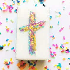 a cross made out of confetti and sprinkles on a sheet of paper