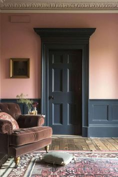 a living room with pink walls and brown furniture in front of a black door on the wall