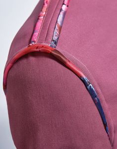 the back side of a pink baseball cap with red stitching and flowers on it