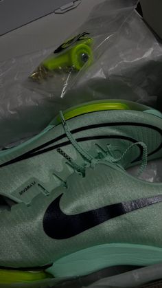 a pair of green and black nike shoes in a box with the shoe laces off