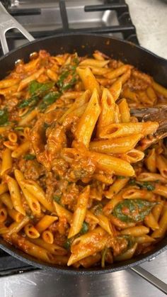 a pan filled with pasta and sauce on top of a stove