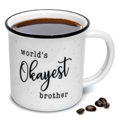 a white coffee mug with the words world's okayest brother on it next to some coffee beans