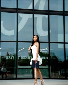 a woman standing in front of a building with her hand on her hip and looking at the camera