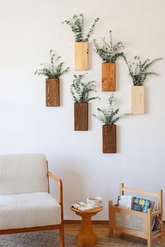 three wooden planters mounted to the wall above a chair and table with magazines on it