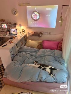 a cat laying on top of a bed in a room with a projector screen