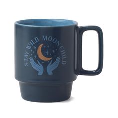 a blue mug with the words stay wild moonchild on it and two hands holding a crescent