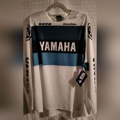 a white and blue shirt with the words yamaha on it hanging from a hanger