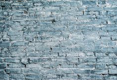 an old blue brick wall that has been painted in shades of gray and light blue