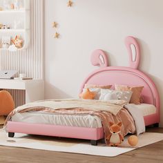 a pink bed with two stuffed animals sitting on the floor next to it in a bedroom