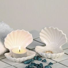 two seashells and a candle on a white tile floor