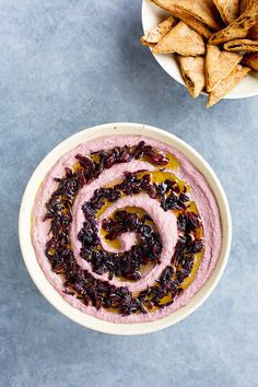 a bowl of hummus and tortilla chips on a blue table with a spiral design in the middle