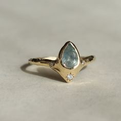 a gold ring with an aqua blue topazte and white diamonds on the side