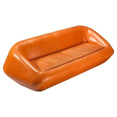 an orange leather couch sitting on top of a white floor