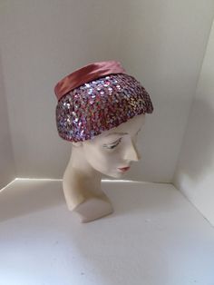 SALE! 10% OFF! Alluring vintage, mid century hat. The shape has a down-turned brim topped with a smaller crown in cinnamon tone satin. The brim is amazing--iridescent lavender color sequins cover the satin creating an unusual color combination as the satin shows through the sequins. For the crown, a 1" band circles it ending in a 4" bow at the back. The satin and sequins sit on a stiff platform. No maker label Size: 4 1/2" tall; 3 1/2" brim at front, 1" at back; 22" inner band circumference Cond Vintage Purple Hat With Short Brim, Vintage Short Brim Purple Hat, Vintage Purple Party Hat, Retro Curved Brim Party Hat, Vintage Pink Hat For Evening, Vintage Pink Costume Hats And Headpieces For Party, Vintage Pink Mini Hat With Curved Brim, Vintage Pink Party Hat And Headpiece, Vintage Pink Evening Hat