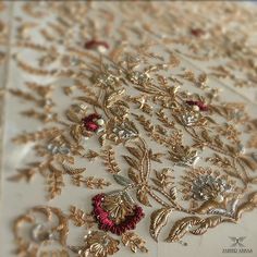 an embroidered fabric with gold and red flowers on it