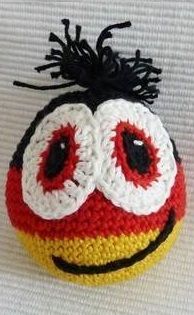 a crocheted ball with eyes and hair