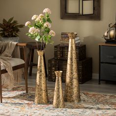 three vases with flowers in them sitting on a rug next to a chair and table