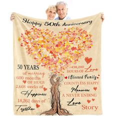 an elderly couple holding up a 50th anniversary blanket with the names and dates on it