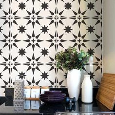 a black and white tiled wall in a kitchen with two vases on the counter