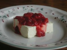 a piece of cheesecake with strawberry topping on a white and floral plate, ready to be eaten