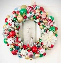 a christmas wreath hanging on the front door with ornaments around it and a santa clause ornament