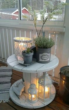 a white table topped with potted plants next to a window filled with candles and other items