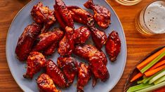 chicken wings and carrots on a plate next to a glass of beer with celery