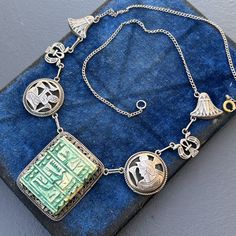 Vintage ~ Art Deco ~ Egyptian revival ~ silver ~ pendant choker necklace with carved Egyptian hieroglyphics on clay /fiancé Bead ~Back has a chain with replaced circular spring clasp . Unsigned acid tested for silver ( atleast 800 silver ). Dates : early  20th century  Materials  silver (except for replaced clasp ) fiancé Bead /slab Measurement:  necklace is 20  inches in length x 5/8 inches max width ~ Pendant adds 1 1/2 inches in drop length x 1 1/4 inches wide  Weighs 34 grams  Condition : Good  antique condition with  some light surface wear to metal and fiancé Bead ~ clasp is a replacement but in good working order and is made of brass  . Please Note ~ As vintage items are previously loved /used please do expect some minor wear like surface wear /dents /dings and metal discoloration . Ceremonial Symbolic Etched Jewelry, Symbolic Ceremonial Etched Jewelry, Symbolic Etched Jewelry For Ceremonial Occasions, Collectible Etched Amulet Jewelry, Collectible Art Deco Carved Jewelry, Art Deco Carved Collectible Jewelry, Vintage Silver Carved Jewelry, Vintage Carved Silver Jewelry, Carved Silver Medallion Jewelry