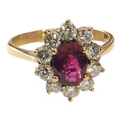 a ring with an oval shaped red stone surrounded by small white and yellow diamond accents