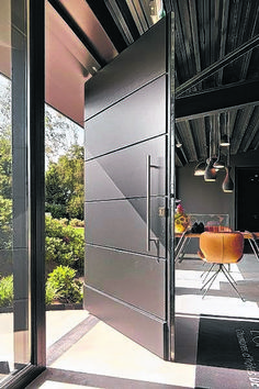 an open door leading to a dining room with chairs and table in the background on a sunny day