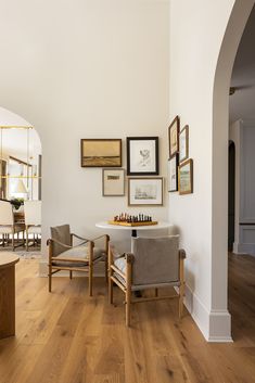 a living room filled with furniture and framed pictures on the wall above a chess table