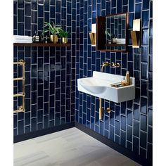 a blue tiled bathroom with gold fixtures and mirrors on the wall, along with a white sink