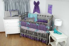 a baby crib with purple and teal bedding