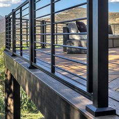 an outdoor deck with wicker chairs and railings overlooking the mountains on a sunny day