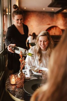 a woman pouring wine into a glass at a restaurant