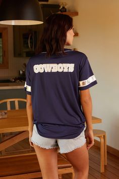 A classic baseball style jersey featuring Americas favorite football team, the Dallas Cowboys. Featuring a functional button front with contrast white piping, white star print on chest, silver foil sleeve stripes, and Cowboys white and silver foil print on the back. 100% Poly Jersey Model height 5' 9", Bust 34", Waist 25", Hip 36", wearing size small Machine wash cold with like colors, tumble dry low Style CWK0029 Game Day Jersey With Graphic Print And Baseball Collar, Collegiate Short Sleeve Baseball Jersey With Moisture-wicking, Thrift Store Clothes, Vintage Dallas Cowboys Sweatshirts, Silver Foil Print, Cowboys Jersey, Dallas Cowboys Jersey, Silver Foil Printing, Thrift Store Outfits