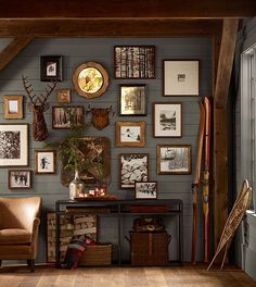 a room filled with lots of framed pictures on the wall next to a brown chair