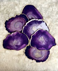 four purple dishes sitting on top of a white rug