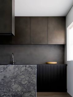 a kitchen with black cabinets and marble counter tops