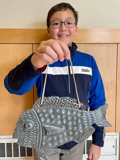 a young boy is holding a metal fish