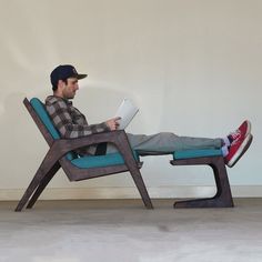 a man sitting in a chair with his feet up on the floor and reading a book