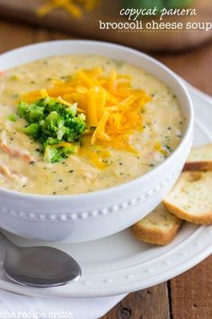 a white bowl filled with broccoli cheese soup and crackers on the side